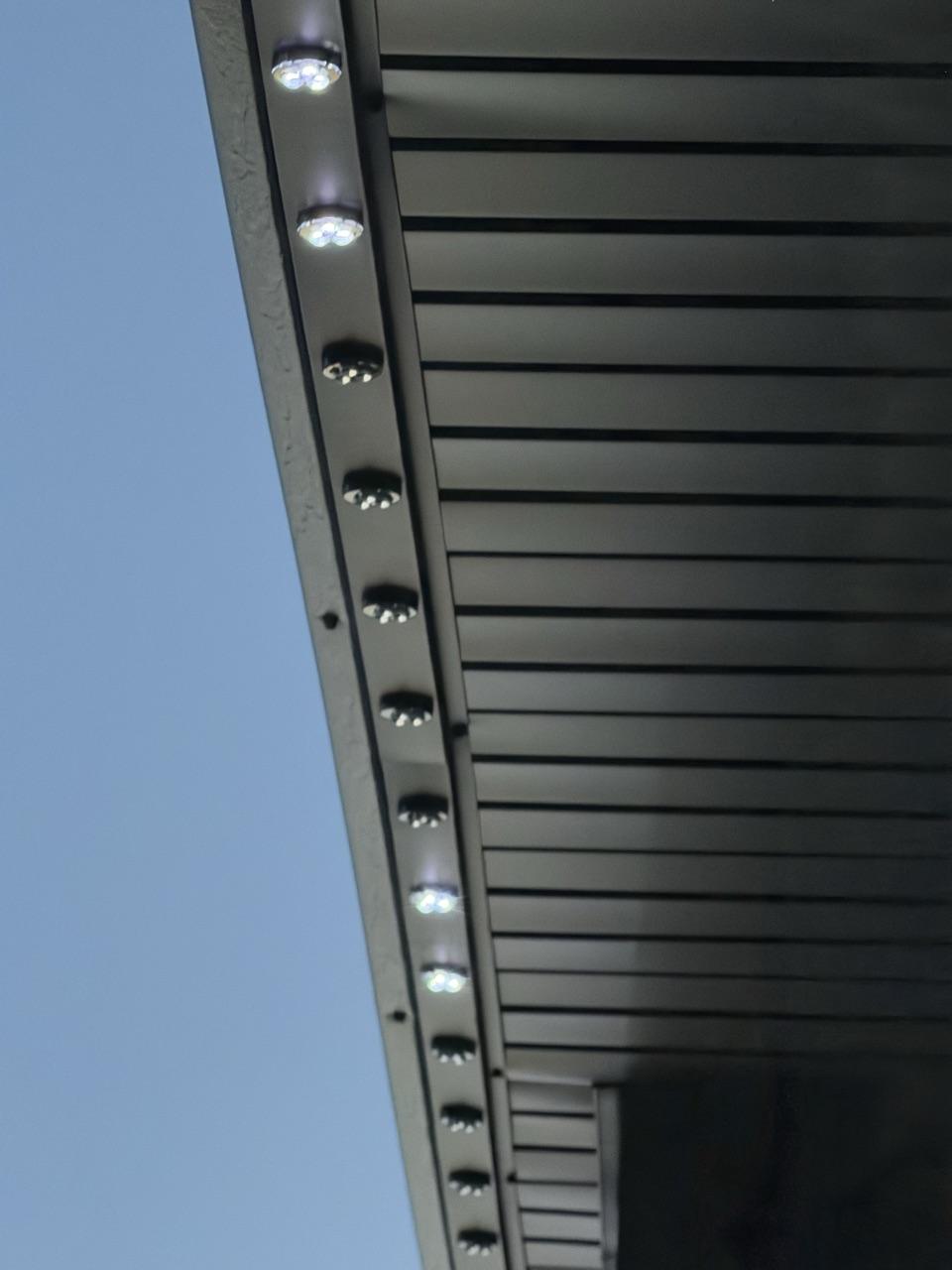 Black GlowPros track and lit LED pucks installed under a dark eave